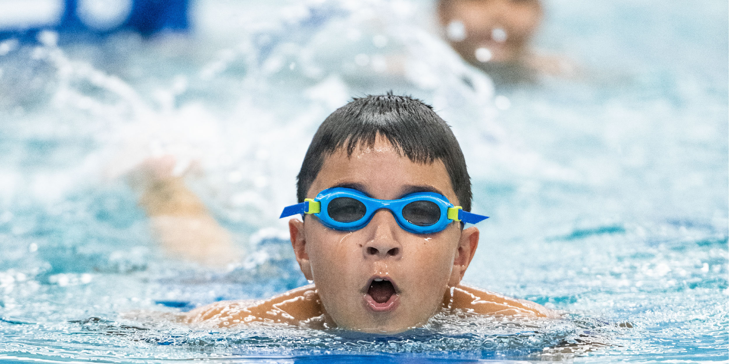 boy-wearing-blue-goggles-swimming-in-pool