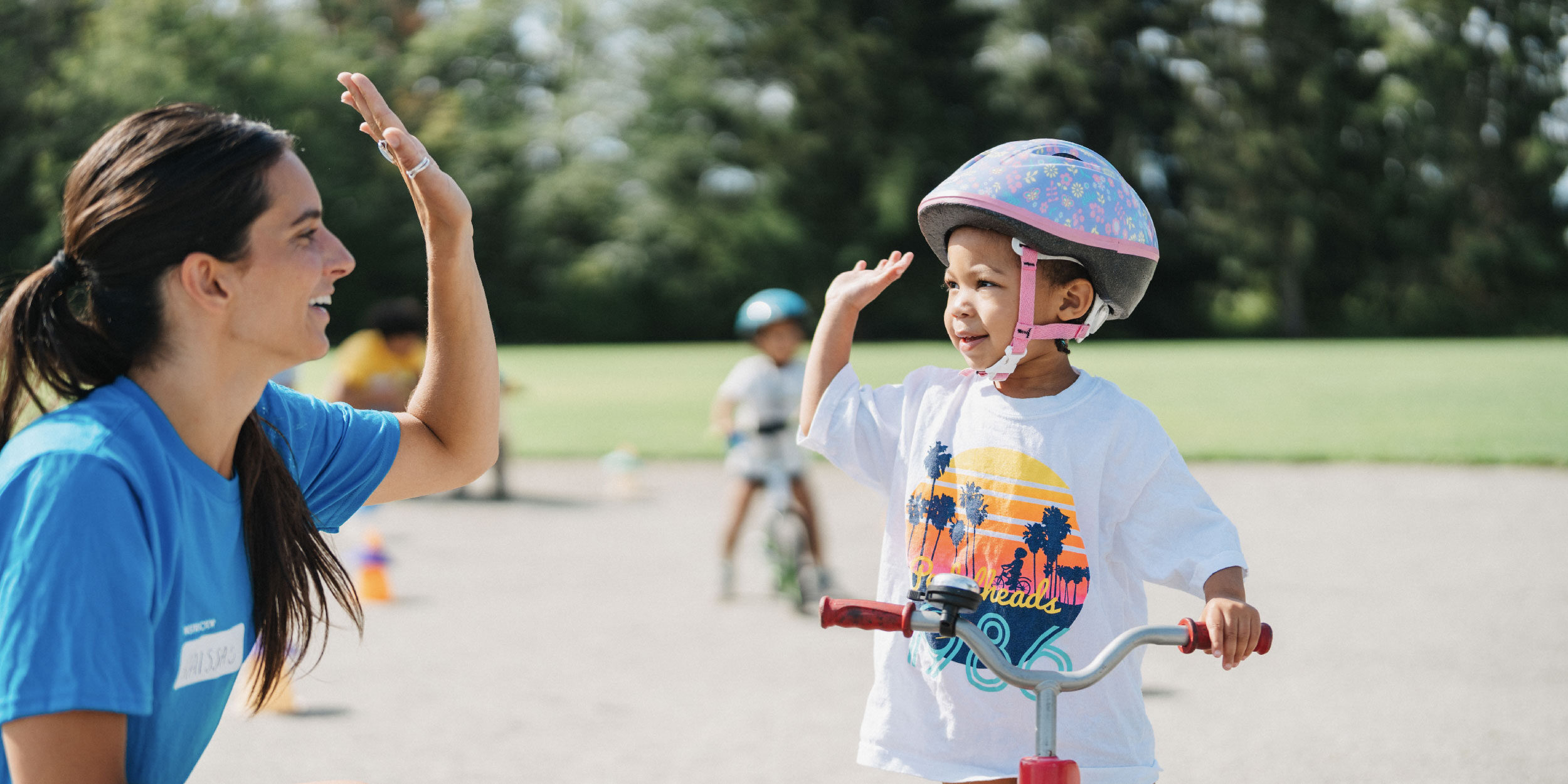 woman-instructor-high-fives-little-girl-on-bike